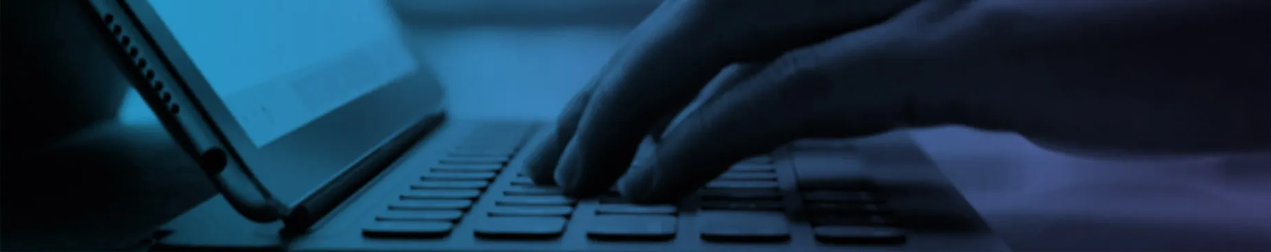 Primer plano de manos escribiendo en un iPad con teclado, representando formación empresarial y aprendizaje digital.